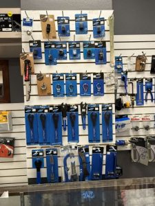 Wall display of packaged bicycle repair tools including wrenches, tire levers, and multi-tools in a retail shop