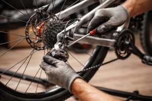 Mechanic adjusting rear derailleur on bicycle with screwdriver