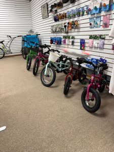 Children’s bicycles lined up on showroom floor with accessories displayed on wall