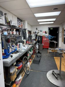 Bicycle repair workshop with tools, workbench, and bike stands in service area.