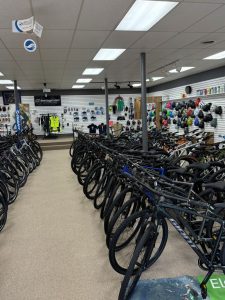 Interior of bicycle shop with rows of bikes and wall displays of helmets and accessories.