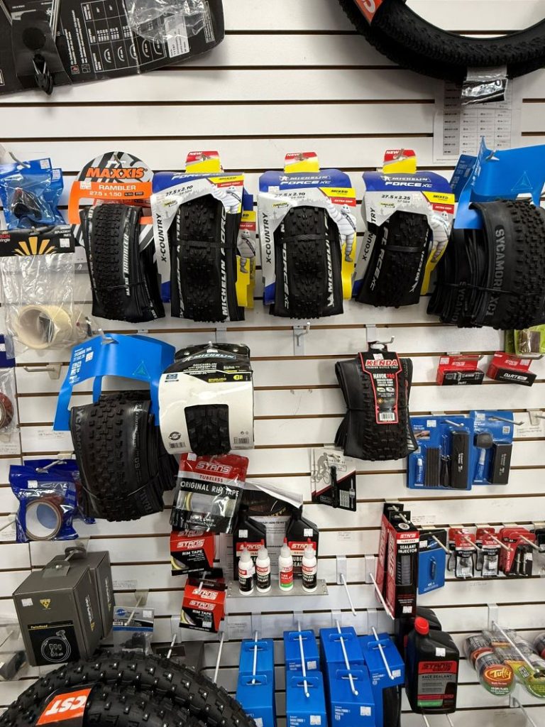 Wall display of bicycle tires, tubes, and maintenance accessories in retail shop.
