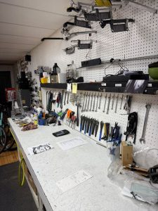 Organized bicycle repair workbench with pegboard wall of tools, wrenches, and maintenance supplies in a bike shop